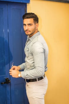 Attractive young man sitting against colorful wall, looking at camera