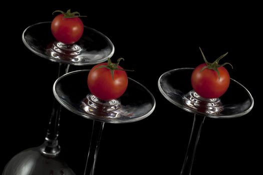 Red cherry tomatoes on the overturned glasses.