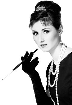 Portrait of a beautiful young woman in retro style with cigarette in mouthpiece in the image of the famous actress Audrey Hepburn. Black and white photography