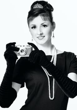 Portrait of a beautiful young elegant woman with a vintage camera isolated on white background. The girl in the image of Audrey Hepburn. Black and white photography