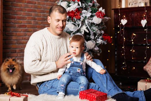 Portrait of happy father and his adorable little daughter among Christmas decorations