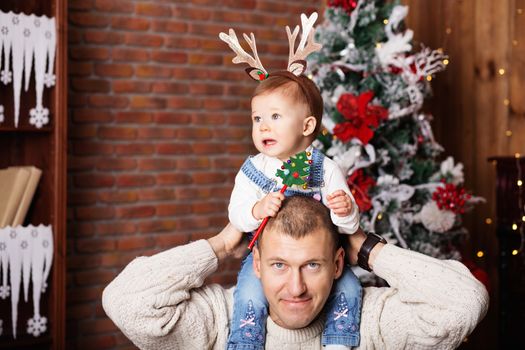 Portrait of happy father and his adorable little daughter among Christmas decorations