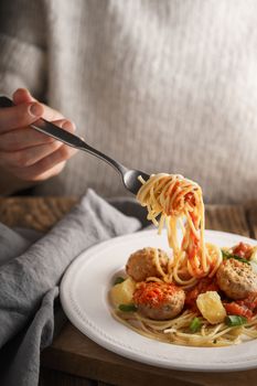 Woman eating spaghetti with meatballs and cheese vertical