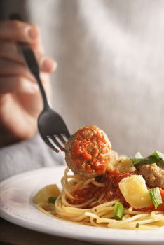 Woman eating spaghetti with meatballs vertical