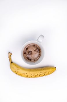 Complete protein Hot Chocolate drink and a banana, isolated on white, overhead shot