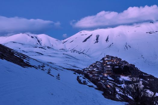 Castelluccio after sunset with the Sibillini mountains in the background with snow on a winter day