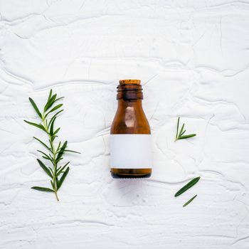 Fresh branch of rosemary  with bottle essential oil setup on white wooden table. Nature aromatherapy spa oil with flat lay on white table.