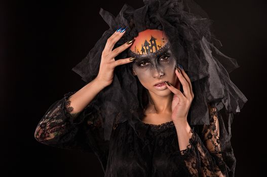 Halloween devil's bride. Portrait of young woman in dark artistic image with scary makeup, veil and terrible picture on her forehead.