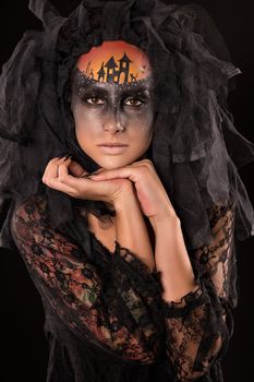 Halloween devil's bride. Portrait of young woman in dark artistic image with scary makeup, veil and terrible picture on her forehead.