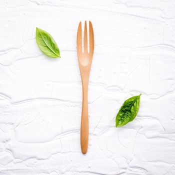 Closeup  fresh sweet basil leaves with fork  on white wooden background. Sweet basil leaves with flat lay .