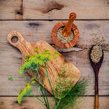 Close up blossoming branch of fennel and dried fennel seeds on rustic wooden background with flat lay.