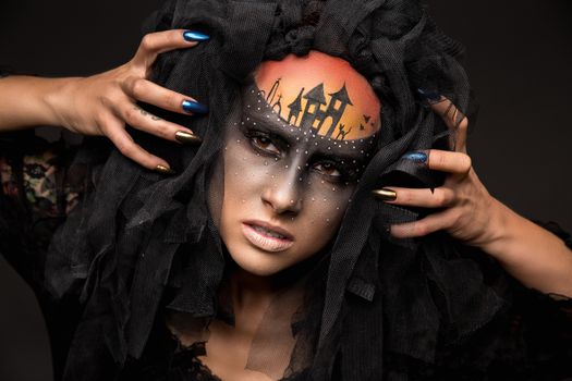 Halloween devil's bride. Portrait of young woman in dark artistic image with scary makeup, veil and terrible picture on her forehead.