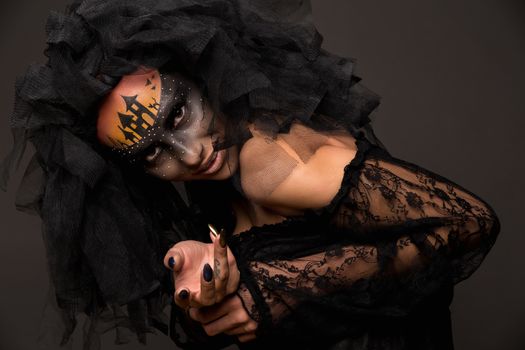 Halloween devil's bride. Portrait of young woman in dark artistic image with scary makeup, veil and terrible picture on her forehead.