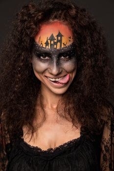 Halloween devil's bride. Portrait of young woman in dark artistic image with scary makeup, veil and terrible picture on her forehead.