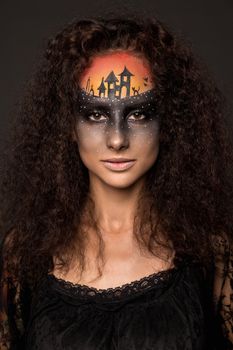 Halloween devil's bride. Portrait of young woman in dark artistic image with scary makeup, veil and terrible picture on her forehead.