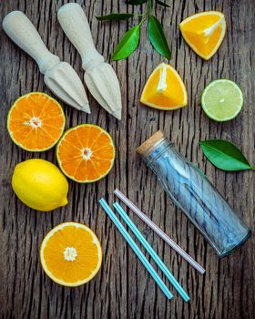 juice with juicer and glass bottle .Fresh lemons, lime and oranges set up on shabby wooden table with flat lay.