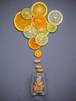 Healthy foods and medicine concept. Bottle of vitamin C and various citrus fruits. Citrus fruits sliced lime,orange and lemon on gray background flat lay.