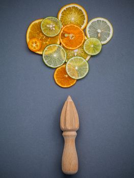 Mixed fresh citrus fruits and wooden juicer for summer citrus juice. Fresh citrus fruits sliced lime,orange and lemon on dark gray background flat lay.