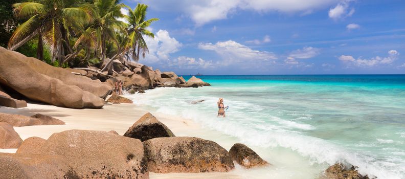 Active sporty woman wearing stylish bikini enjoying swimming and snorkeling at amazing on Anse Patates beach on La Digue Island, Seychelles. Summer vacations on picture perfect tropical beach concept.