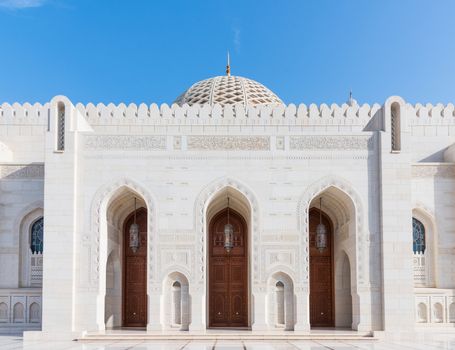 Exterior detail with entrance doors and the dome in the background of the Sultan Qaboos Grand Mosque in Muscat, the main mosque of The Sultanate of Oman.