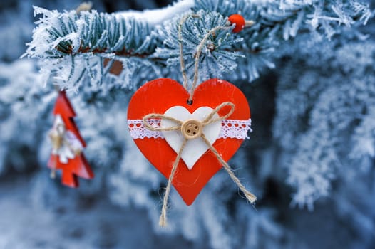 wooden Christmas toys on a beautiful snowy fir tree in winter.