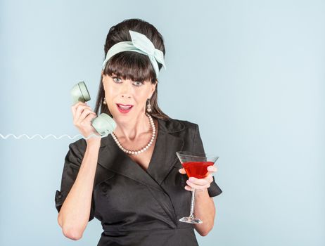 Pretty retro woman in black dress with Cosmopolitan cocktail and phone receiver