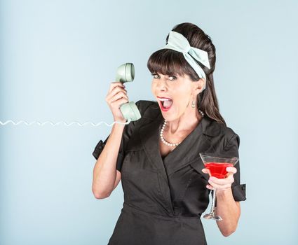 Excited retro woman in black dress with cosmopolitan cocktail and phone receiver
