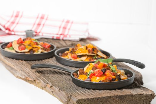 Colorful nachos served on individual cast iron fry pans.