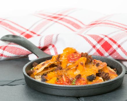 Delicious nachos served in a small cast iron fry pan.