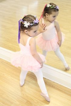 Little ballet girl standing in front of a mirror