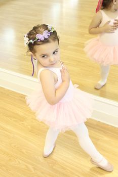 Little ballet girl standing in front of a mirror