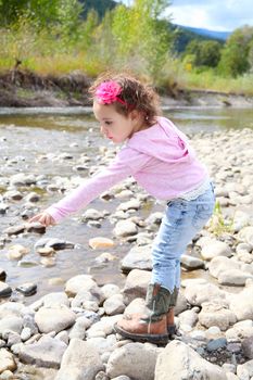 Beautiful brunette toddler playing outside by the river