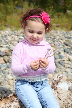Beautiful brunette toddler playing outside by the river