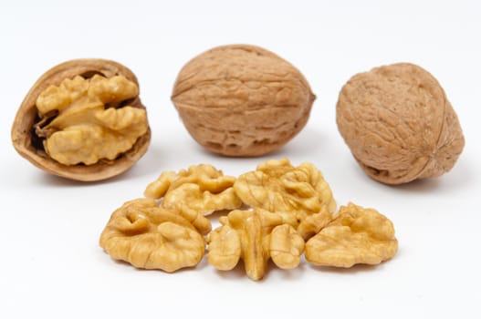 Whole walnuts and walnut kernels on white background