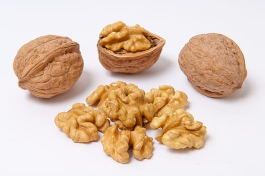 Whole walnuts and walnut kernels on white background