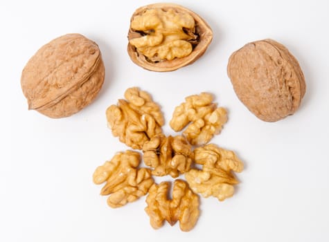 Whole walnuts and walnut kernels on white background