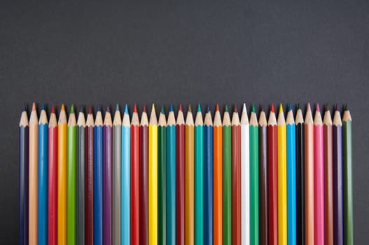 Pattern of color pencils isolated on black background close up