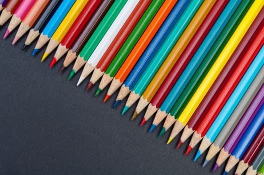 Pattern of color pencils isolated on black background close up
