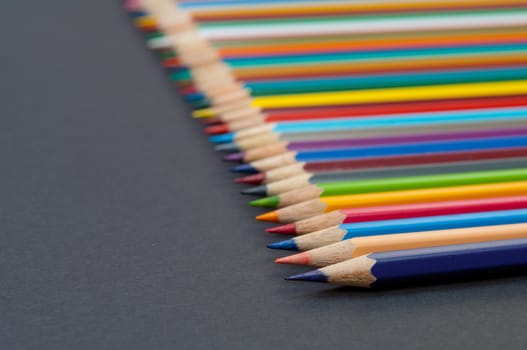 Pattern of color pencils isolated on black background close up
