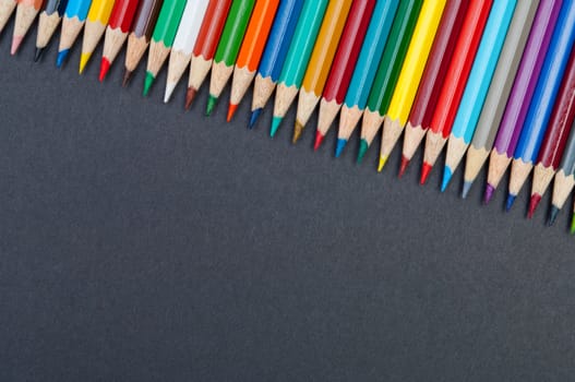 Pattern of color pencils isolated on black background close up