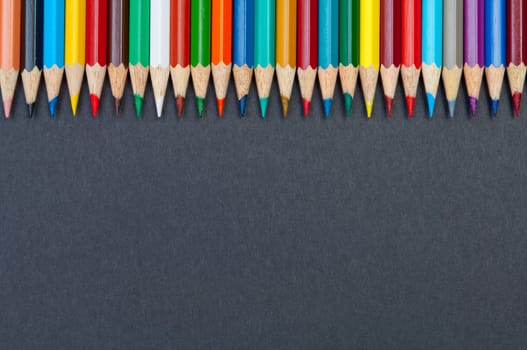 Pattern of color pencils isolated on black background close up