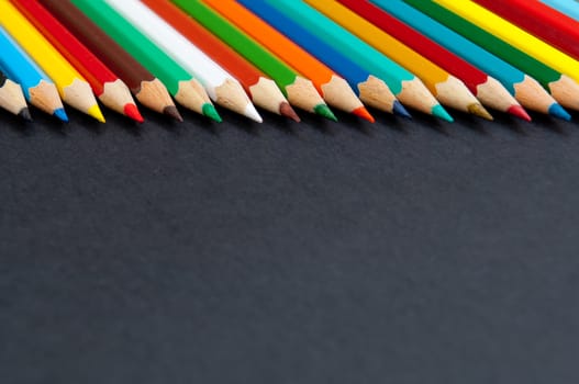 Pattern of color pencils isolated on black background close up