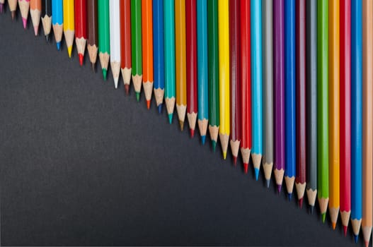 Pattern of color pencils isolated on black background close up