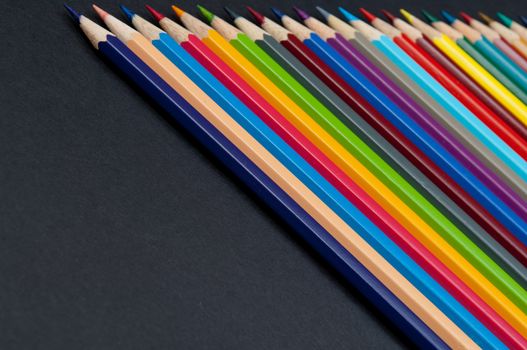 Pattern of color pencils isolated on black background close up