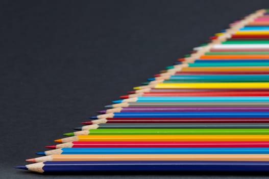 Pattern of color pencils isolated on black background close up