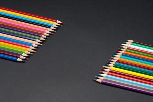Pattern of color pencils isolated on black background close up