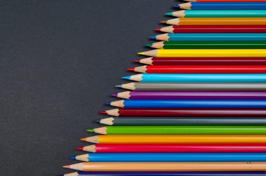 Pattern of color pencils isolated on black background close up