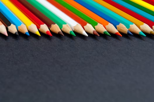 Pattern of color pencils isolated on black background close up