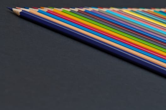 Pattern of color pencils isolated on black background close up