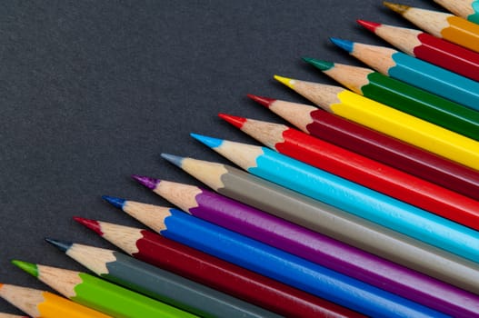 Pattern of color pencils isolated on black background close up